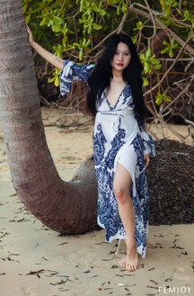 May Poses Nude Under Palm Trees In Tropical Heat, Black Hair Flowing As She Leans Against Bark